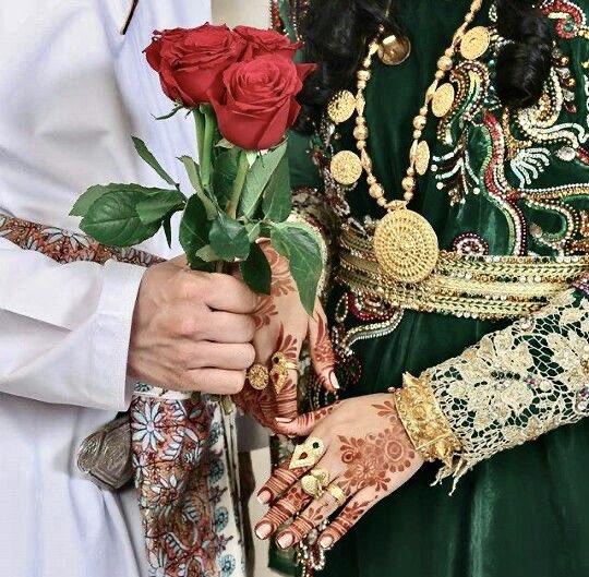 Un joven árabe vestido de blanco, entrega una rosa a una joven vestida de ropa tradicional árabe 